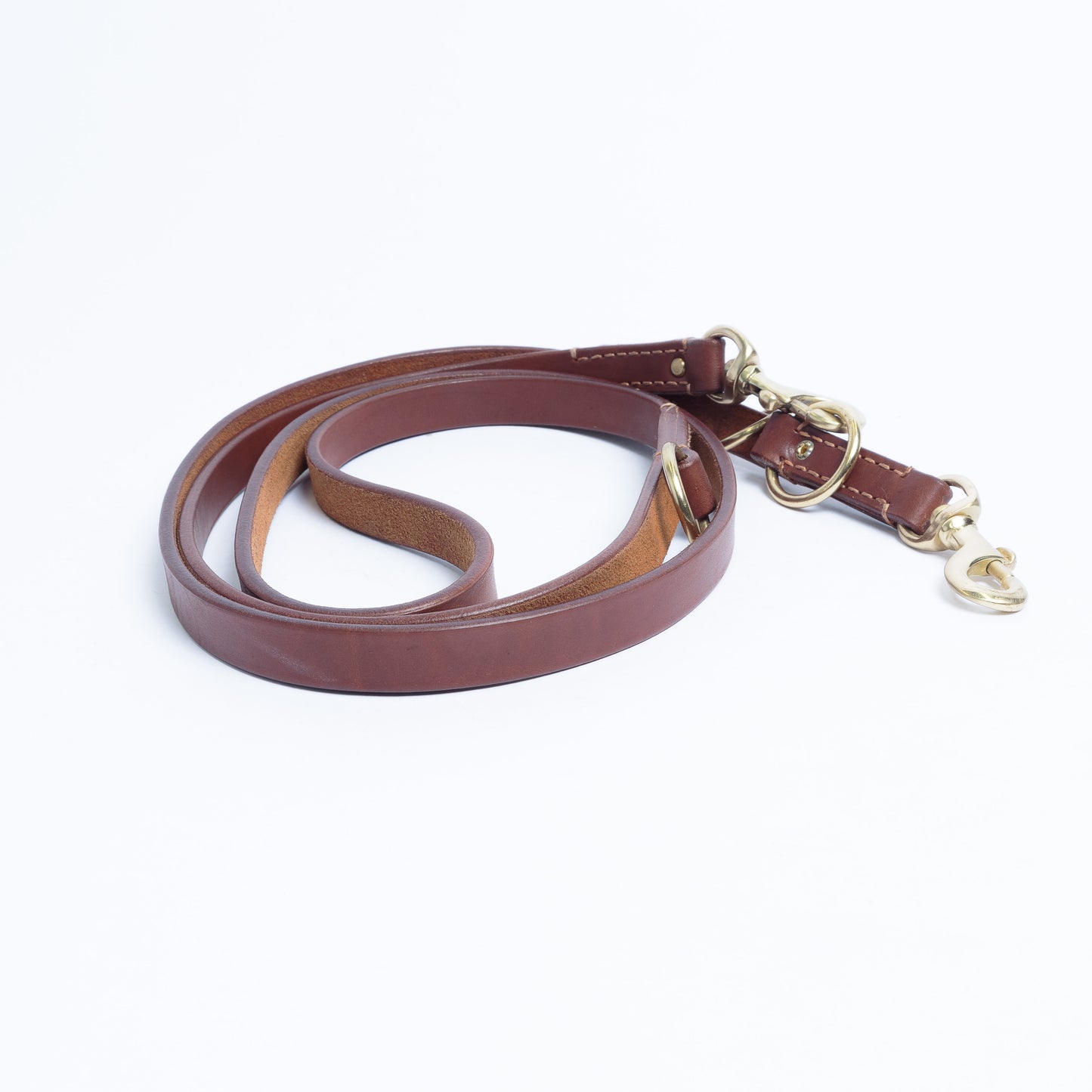 Brown leather dog leash with gold hardware on white background