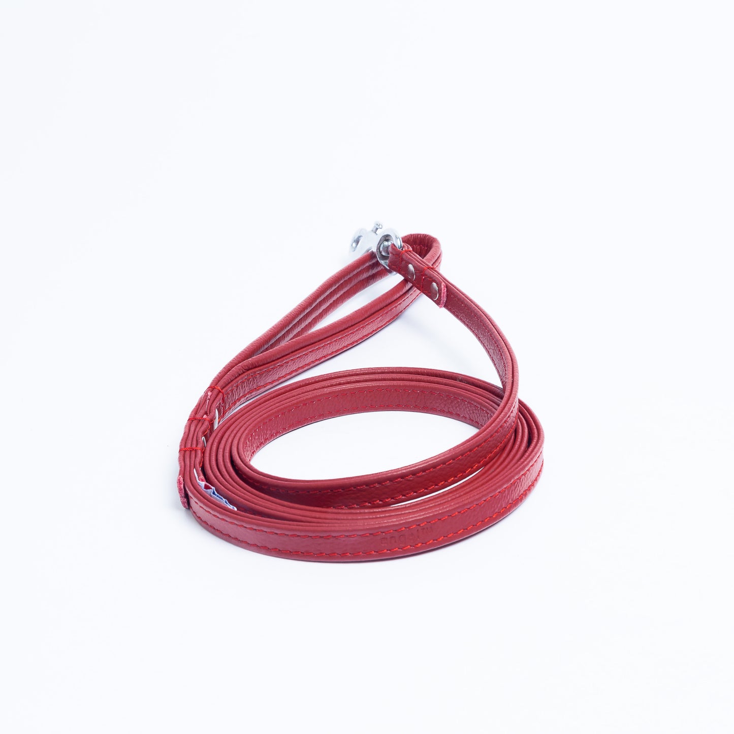 Red leather dog leash coiled on a white background.