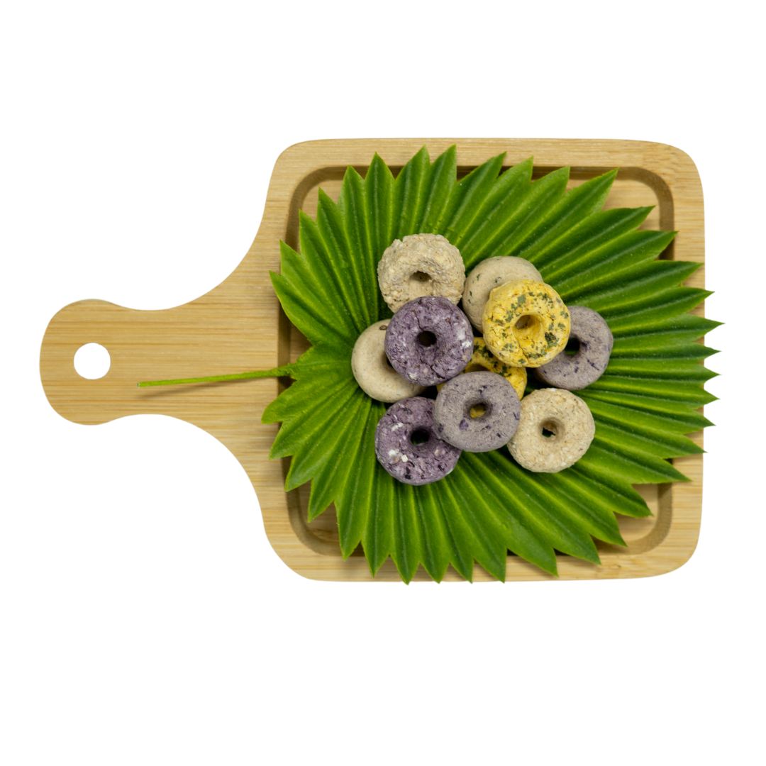 Mixed color donut biscuits on a wooden board with green leaves